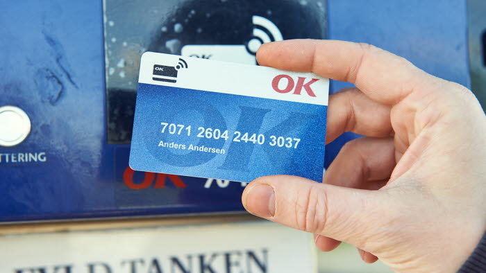 Hånd der holder et OK Truck Diesel-kort op ved en betalingsautomat