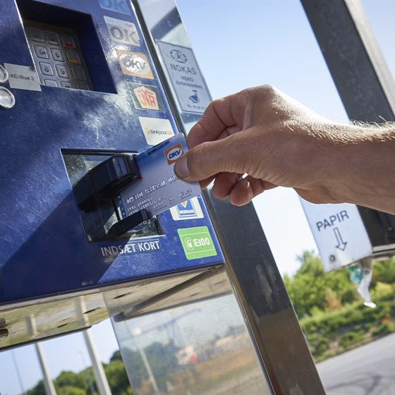 Hånd holder et OK DKV-kort op til en betalingsautomat
