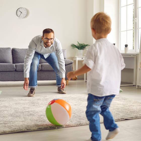 Mand og søn leger med bold i stuen