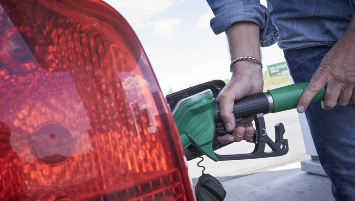 Mand står med hånden på en tankpistol i færd med at tanke brændstof