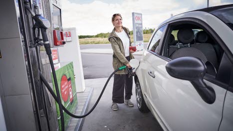 Kvinde i færd med at tanke bil på OK-tankstation