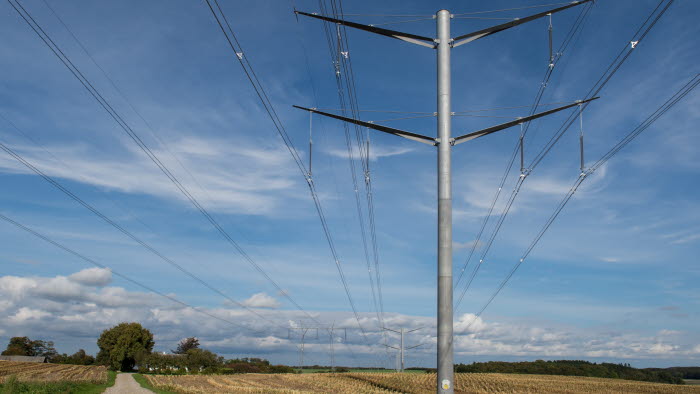 Højspændingsmast på kornmark med blå himmel