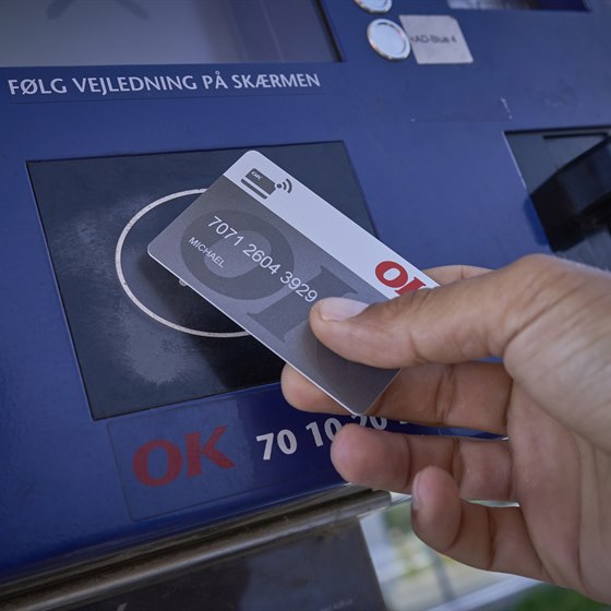 Hånd med OK Erhvervskort ved en betalingsautomat