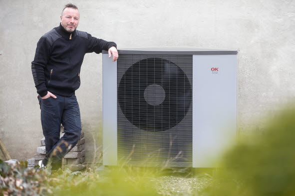 Mand læner sig op ad sit varmepumpeanlæg