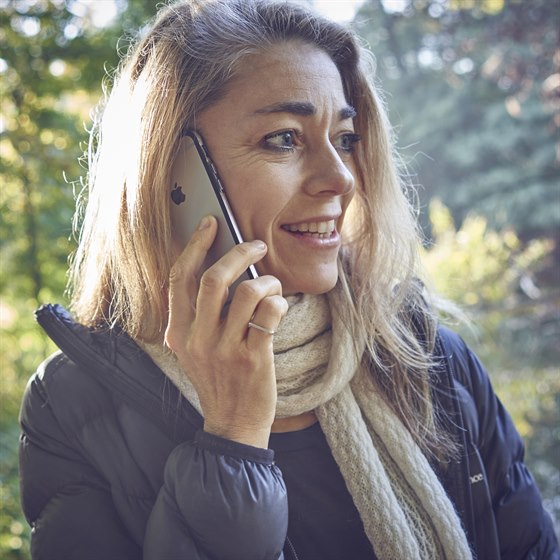 Kvinde står med mobiltelefon op til øret