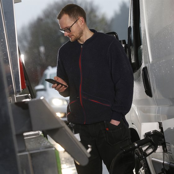 Mand står ved en hvid varebil på en tankstation