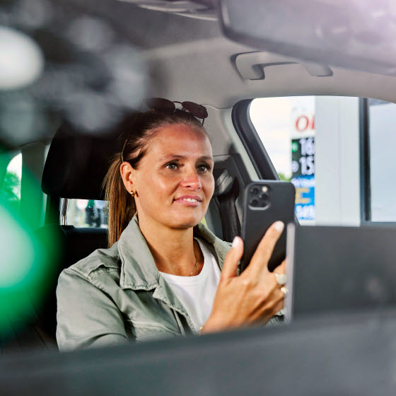 Kvinde sidder med mobiltelefon i bil