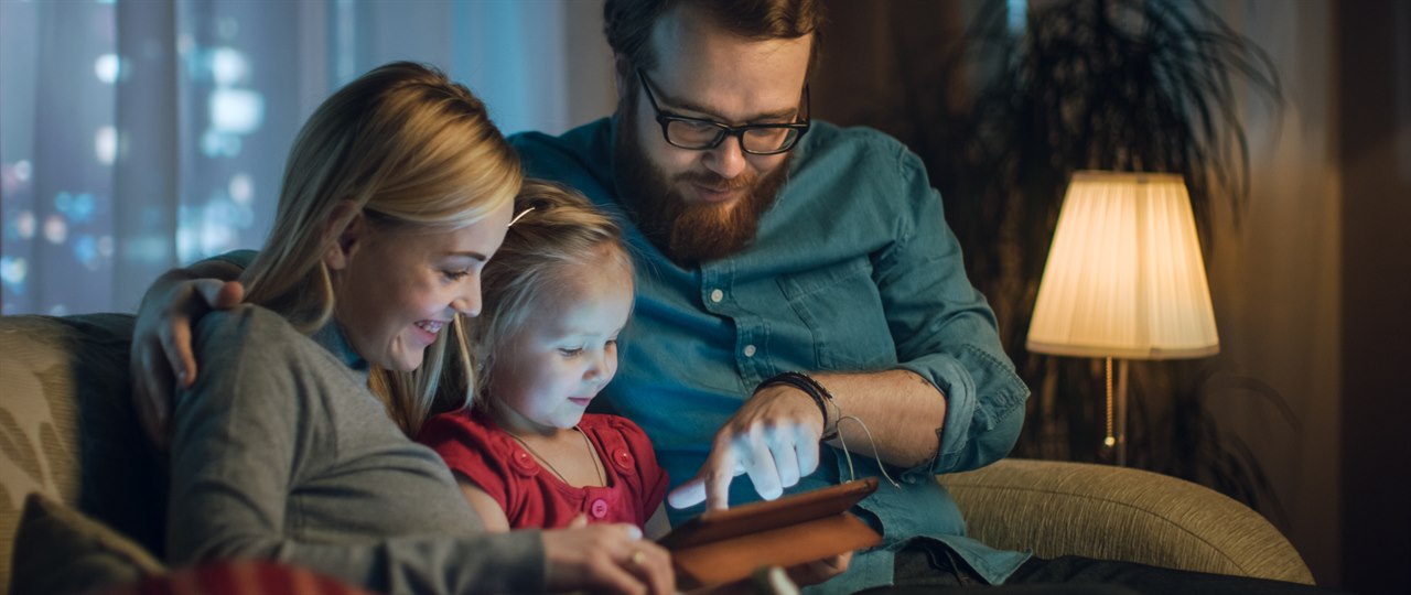 Familie sidder i sofa med tablet