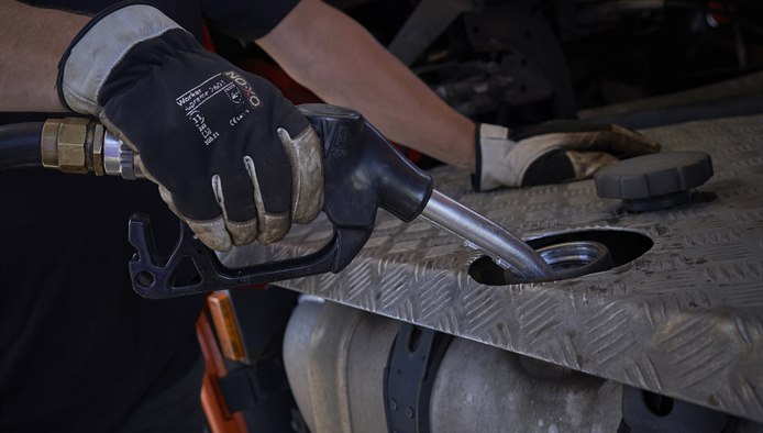 Hånd iført handske i færd med at fylde brændstof på en lastbil