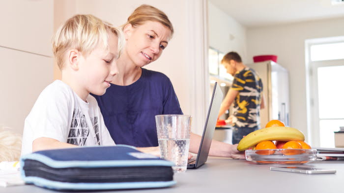 Mor og søn sidder ved spiseborg med PC foran sig
