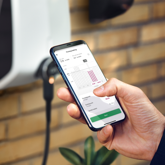 Hånd holder mobiltelefon ved ladeboks