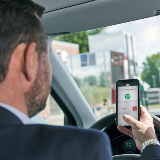 Mand i bil med mobil har OK-appen åben