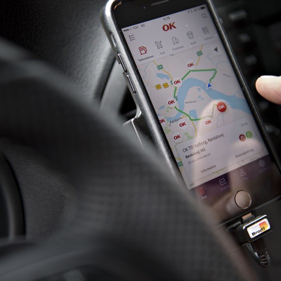 Mobiltelefon i førerkabine på bil med kortvisning af OK's app