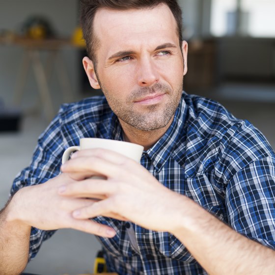 Mand sidder med et kaffekrus og kigger tænksomt ud