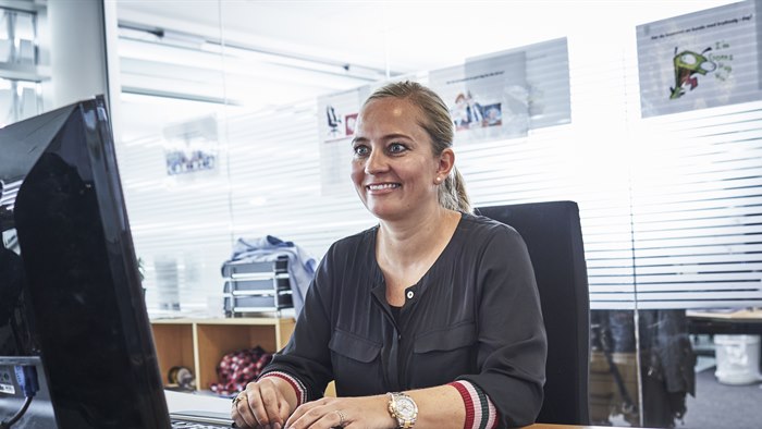 Smilende kvinde sidder på kontor foran computerskærm og tastatur