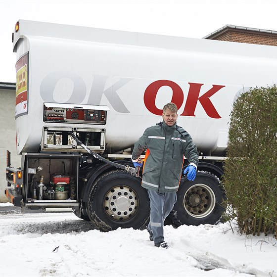 En af OK's tankvognschauffører på vej ind til hus med olieslange i hånden