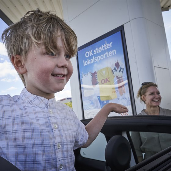 Dreng står og kigger ud af bilens soltag