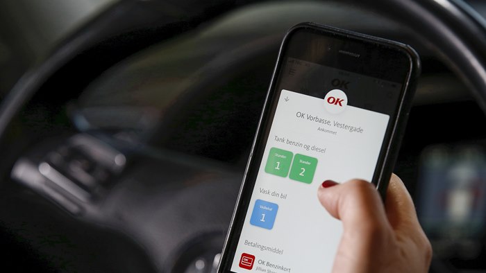 Mobiltelefon med OK's app med valg af tankstander på skærmen