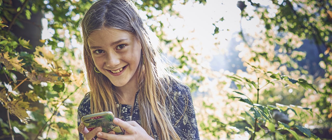 Pige i skoven med sin mobiltelefon
