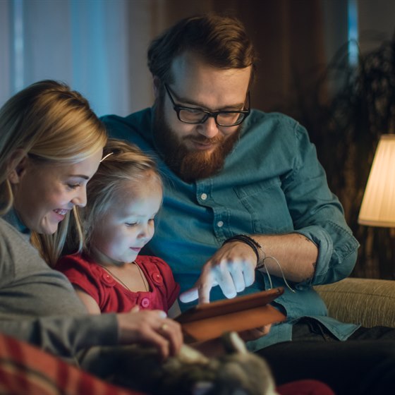 Familie sidder i sofa med tablet