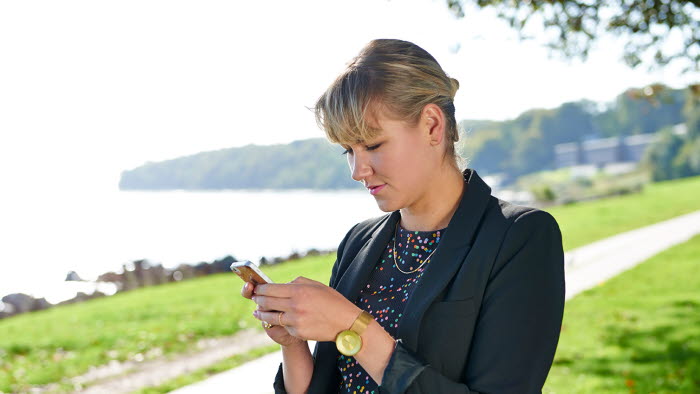 Ung kvinde står med sin mobiltelefoni