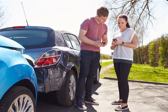 En mand og en kvinde står ved siden af to biler og udveksler information