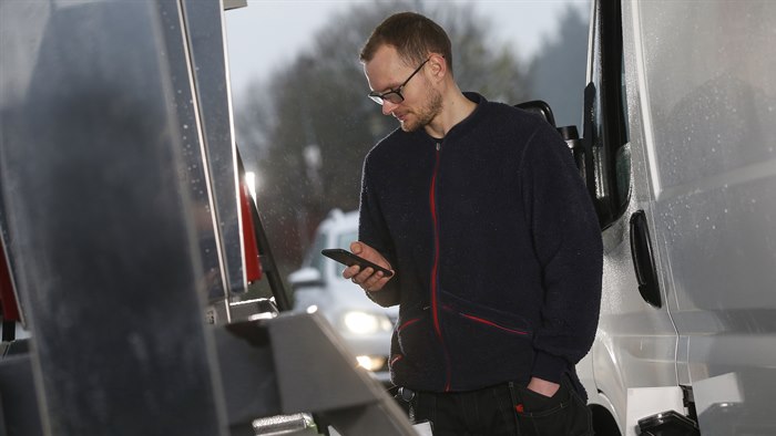 Mand står ved en hvid varebil på en tankstation