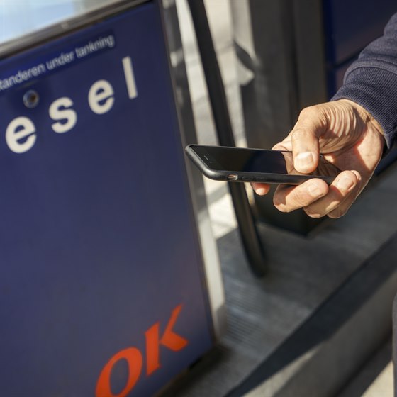 Mand holder mobiltelefon ved en OK Truck Diesel-stander