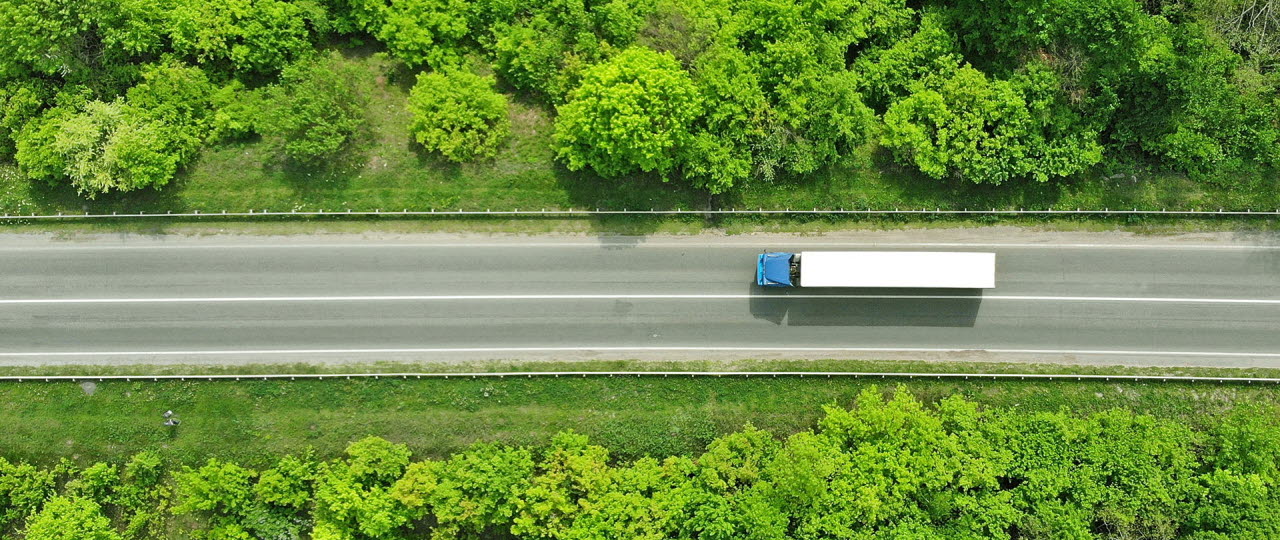 Lastbil på vej i grøn natur set ovenfra