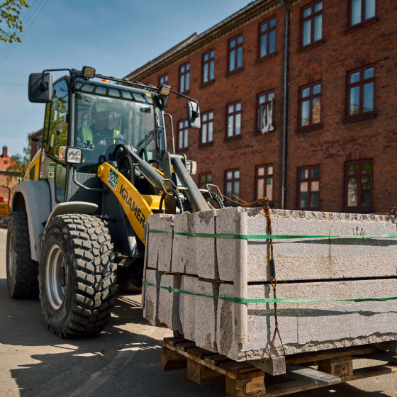 Gummiged kører med en palle med cementblokke