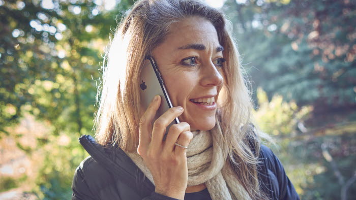 Kvinde står med mobiltelefon op til øret