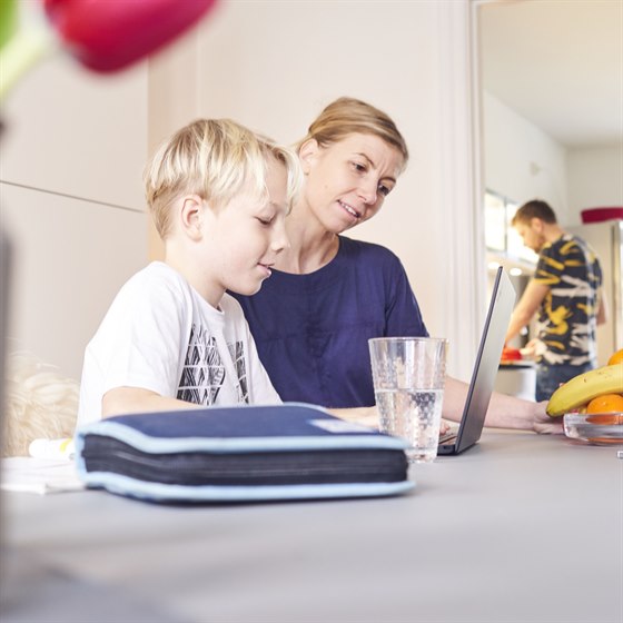 Mor og søn sidder ved spiseborg med PC foran sig
