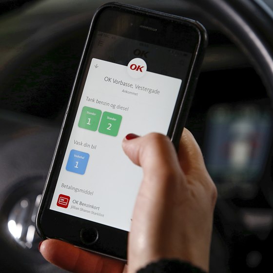 Mobiltelefon med OK's app med valg af tankstander på skærmen
