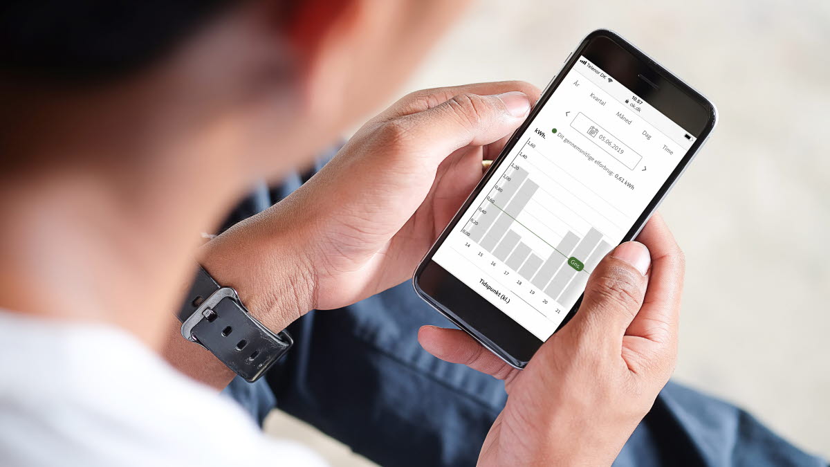 Mand sidder med mobiltelefon og tjekker elforbrug på selvbetjeningen Min OK