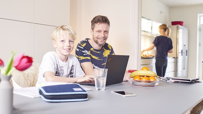 Far og søn ved spisebord med PC og penalhus foran sig