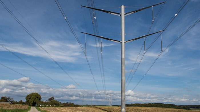 Højspændingsmast på kornmark med blå himmel