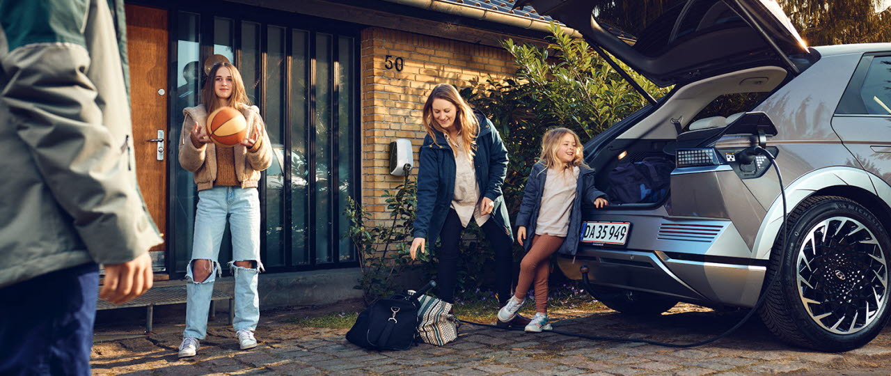 Familie ved elbil med hjemmelader