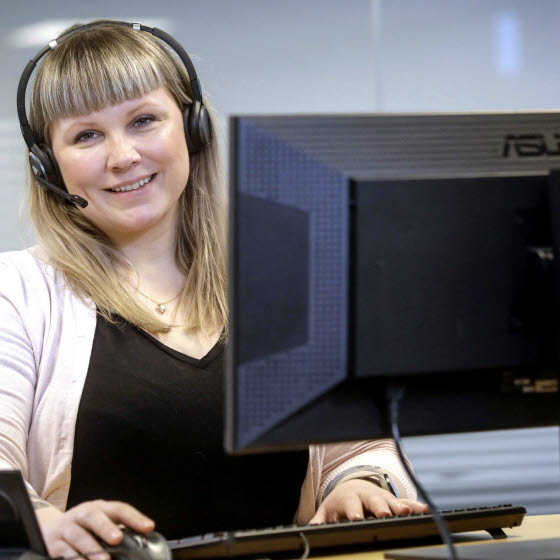Kvinde sidder i OK's kundeservice med headset