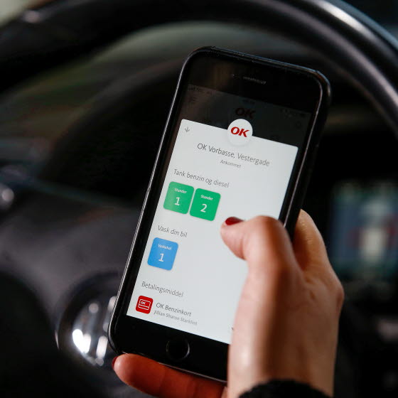 Mobiltelefon med OK's app med valg af tankstander på skærmen