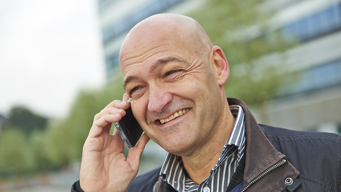 Smilende mand holder mobiltelefon op til øret