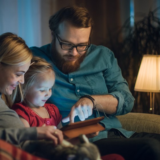 Familie sidder i sofa med tablet