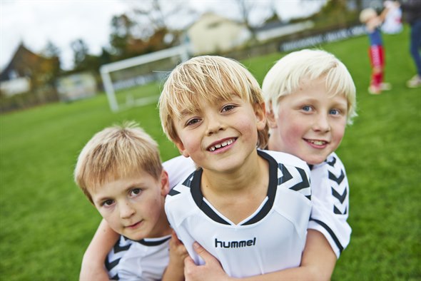 Tre fodbolddrenge iført OK fodboldtrøjer