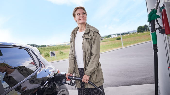 Kvinde i færd med at tanke bil hos OK