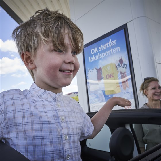 Dreng står og kigger ud af bilens soltag