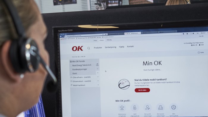 Kvinde sidder ved computerskærm med OK's selvbetjening Min OK foran sig