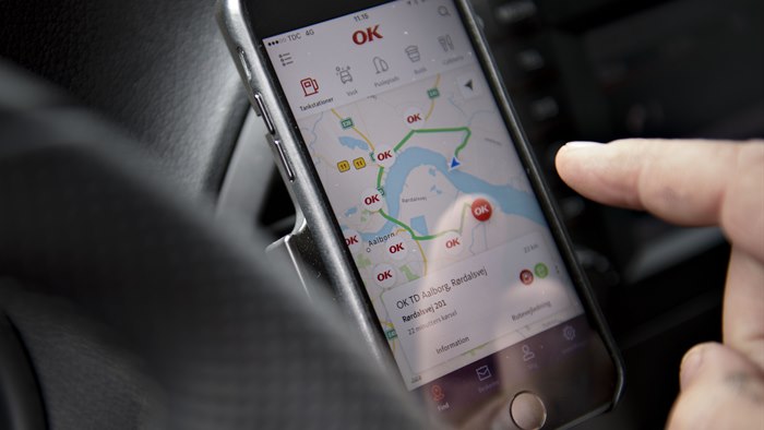 Mobiltelefon i førerkabine på bil med kortvisning af OK's app