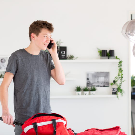 Ung mand i færd med at pakke sportstaske taler i mobiltelefon