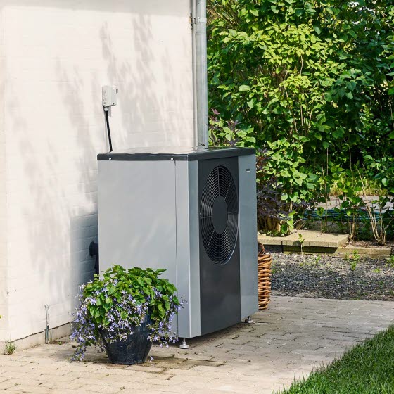Varmepumpe står foran hus med et cafesæt på terrassen