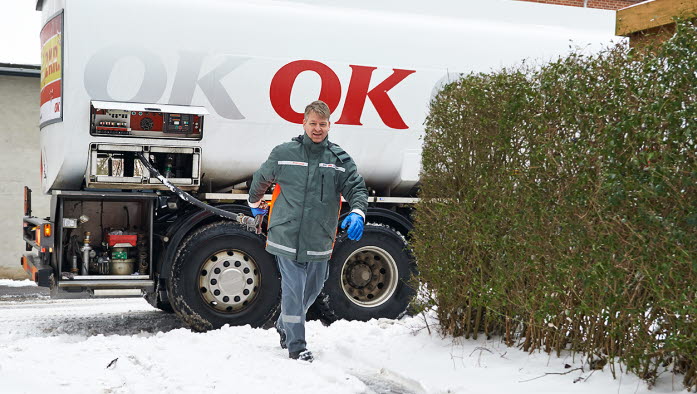 En af OK's tankvognschauffører på vej ind til hus med olieslange i hånden