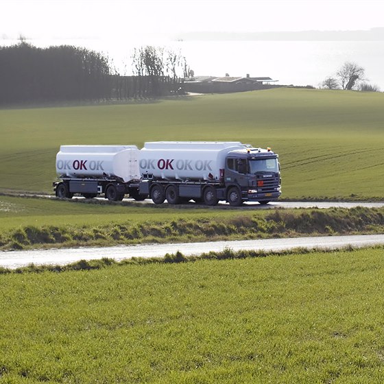 OK tankvogn med hænger på vej gennem landskab med grønne marker